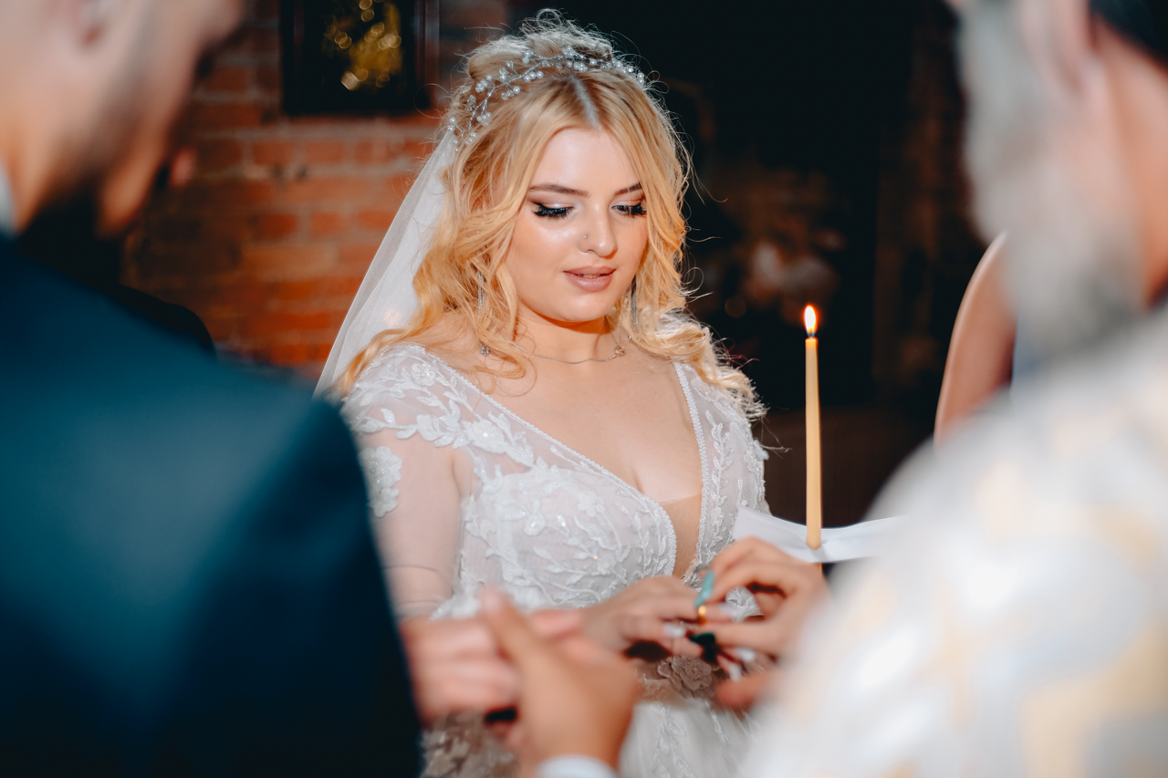 Beautiful bride in wedding gown holding candle during a romantic ceremony.