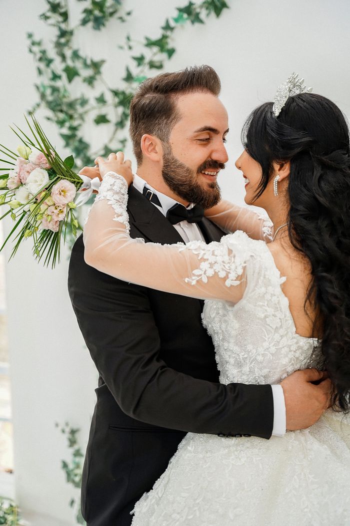 Smiling bride and groom embrace lovingly in elegant wedding attire.